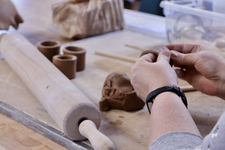 Hands working with clay and tools on a table