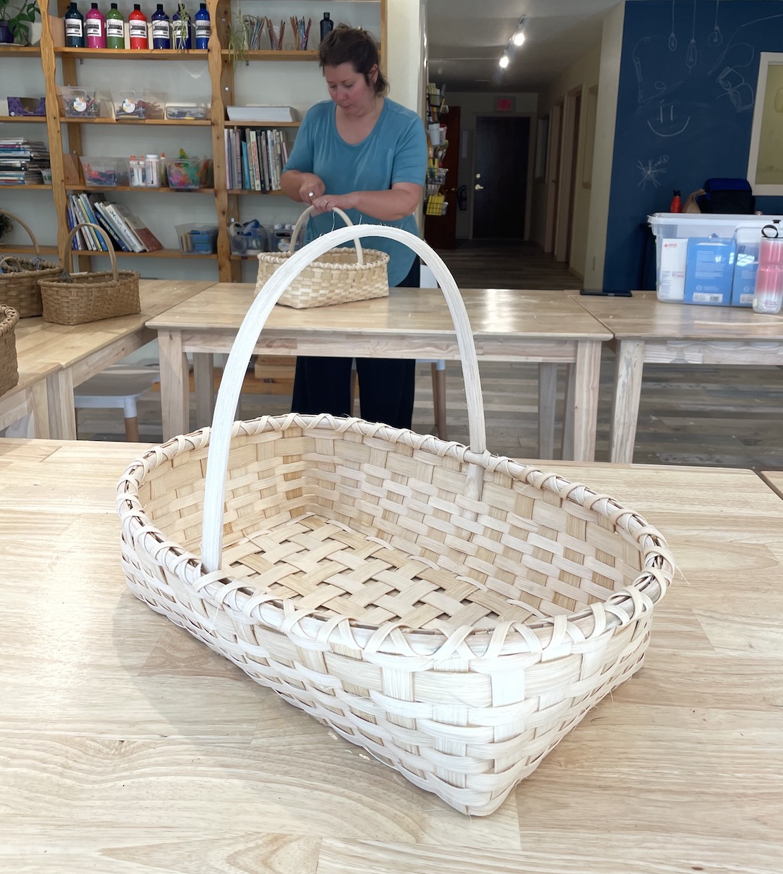 rectangular woven basket on table with woman in the background