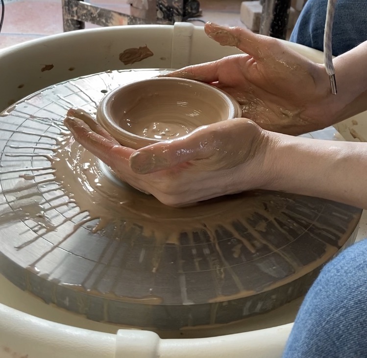 Hands picking up wheel thrown clay bowl