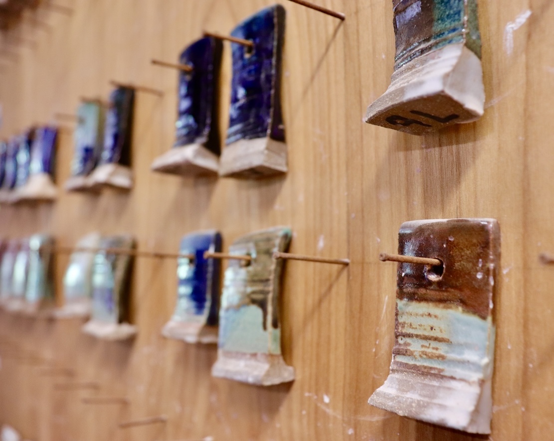 Clay test tiles with glazes hanging on a wall