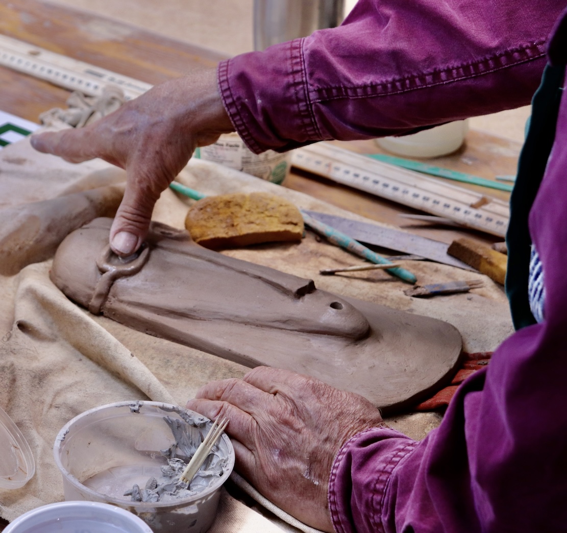 Hands working with clay creating a sculptural face