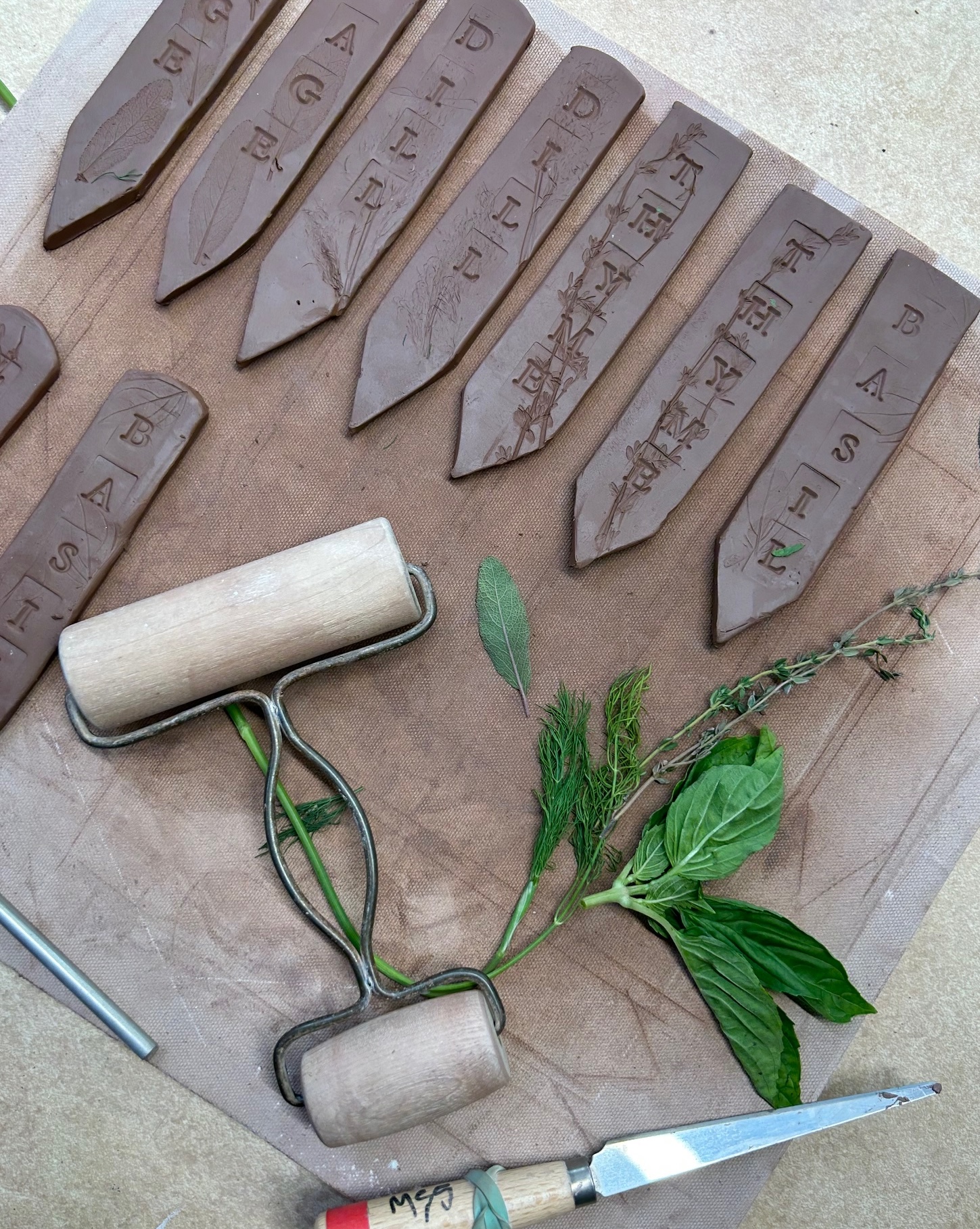 clay garden markers with fresh herbs and clay tools