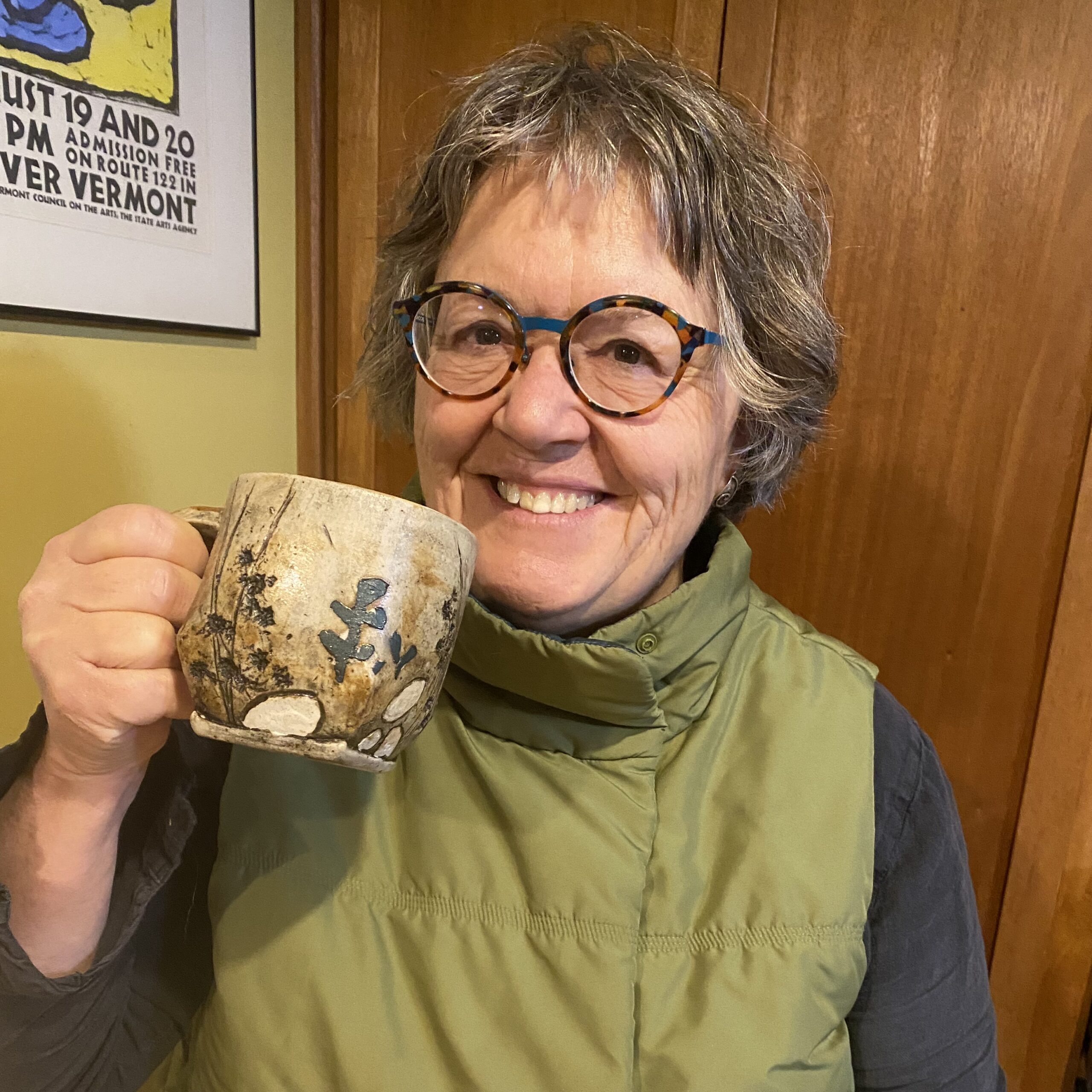 Woman in green vest holding hand made mug