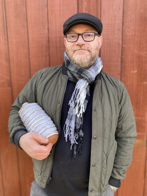 Man in scarf holding hand made vase